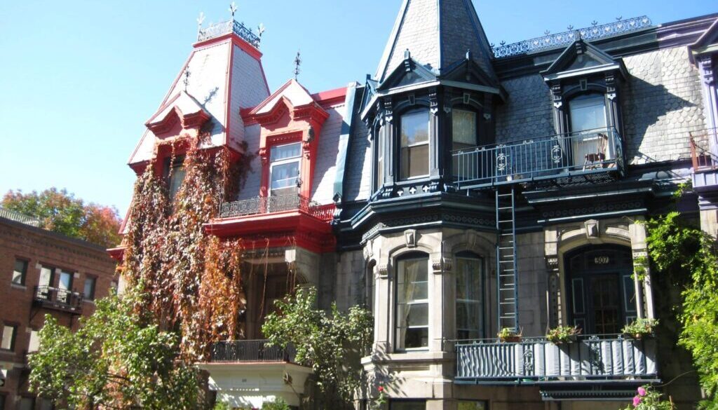 Colorful Victorian-style houses with intricate architectural details and climbing plants in Montreal.