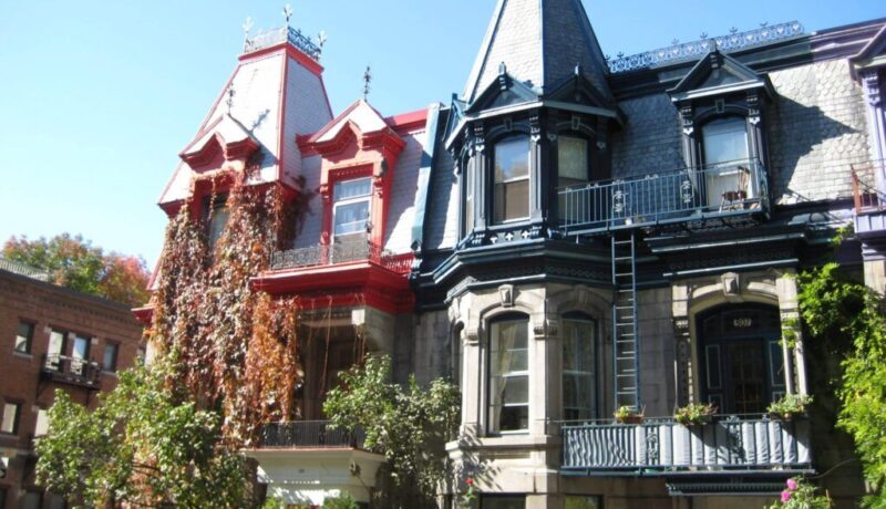 Colorful Victorian-style houses with intricate architectural details and climbing plants in Montreal.